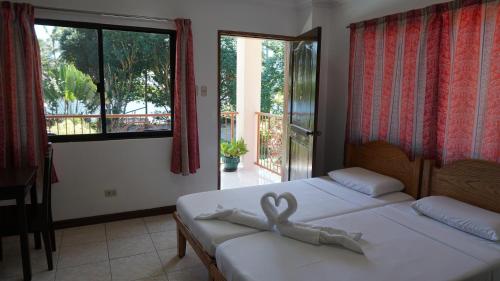 Zamboanguita威尔海滩潜水度假酒店的一间卧室设有两张床和大窗户