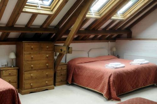 劳斯Brackenborough Hall Coach House - Granary的阁楼卧室设有两张床和天窗。