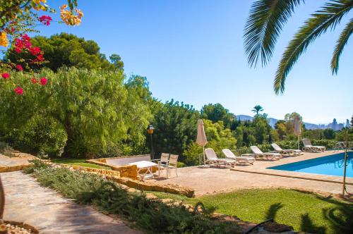 贝尼多姆Villa Altozano with pool, barbeque, large garden, and fantastic sea views的一个带躺椅的游泳池,并种植了棕榈树