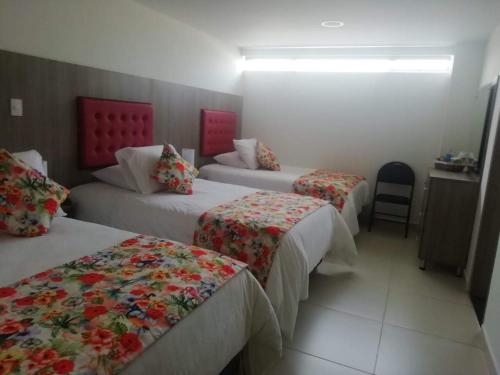 马尼萨莱斯Hotel Grato Manizales的酒店客房,设有三张床和椅子