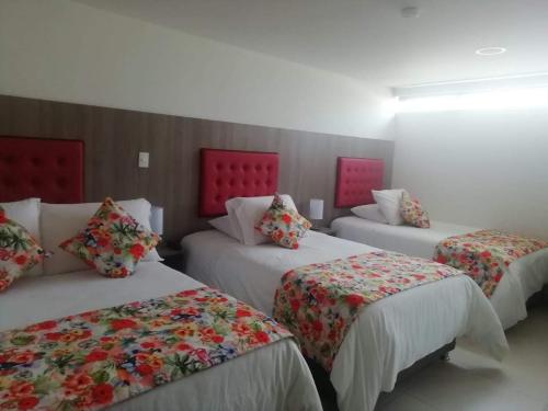 马尼萨莱斯Hotel Grato Manizales的带红色床头板的客房内的三张床