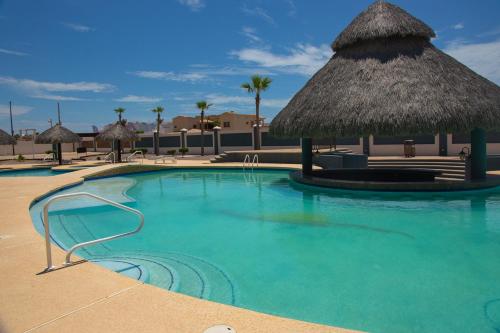 佩尼亚斯科港Linda Vista 106的一个带草伞的游泳池和一个度假村