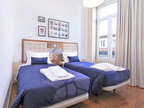 波尔图Vanzeleres 285的一间卧室设有两张带蓝色床单的床和窗户。