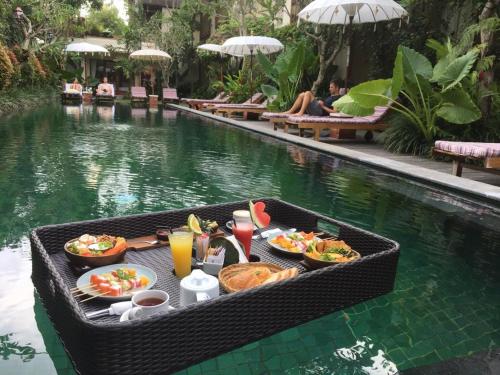 乌布萨博迪拉乌布酒店的游泳池旁桌子上的一盘食物