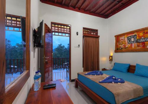 龙目岛库塔Kintari Indah Homestay的一间卧室设有一张床、一台电视和窗户。