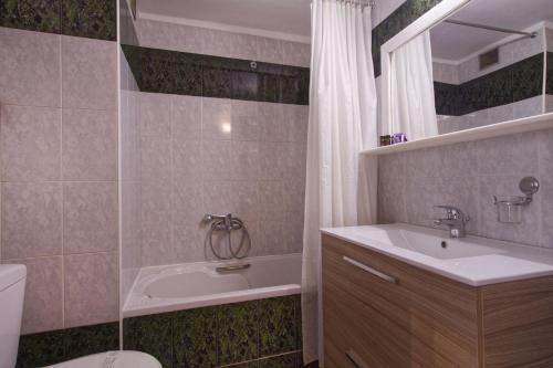 沃洛斯纳菲利酒店的带浴缸、盥洗盆和卫生间的浴室