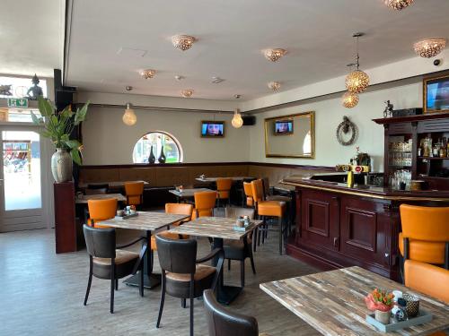 斯塔茨卡纳尔City Hotel Restaurant Stadskanaal的一间带桌椅的餐厅和一间酒吧