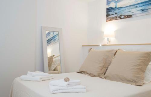 休达德亚Hotel Romantic Los 5 Sentidos的一张带毛巾的白色床和镜子