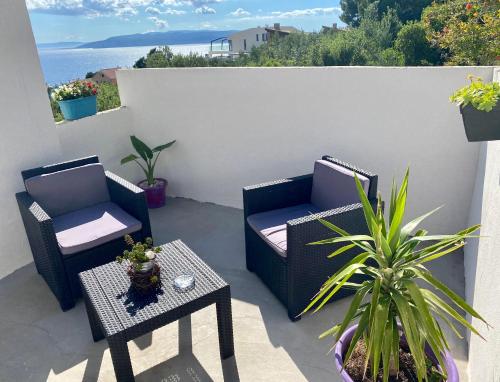 马卡尔斯卡Luxury apartments Nikolina Sea&City view的庭院设有两把椅子和一张桌子,种植了植物