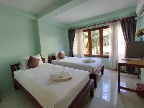 南邦Ban Mae Boonthong的配有窗户和电视的客房内的两张床