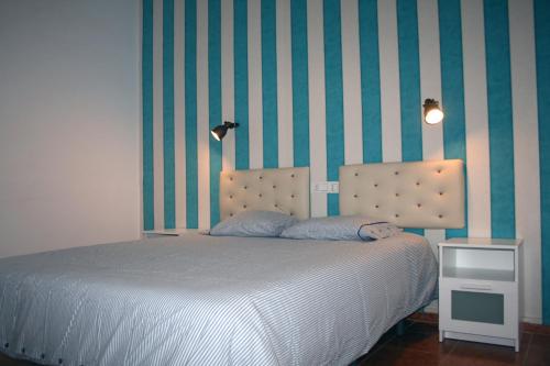 卡门港布兰卡斯简易别墅酒店的一间卧室配有一张床和条纹墙