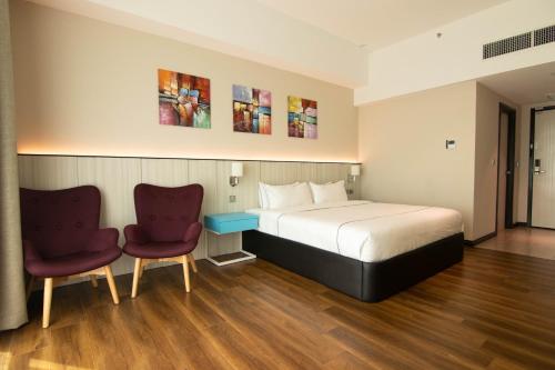 斯里巴加湾市Higher Hotel的酒店客房,配有一张床和两把椅子