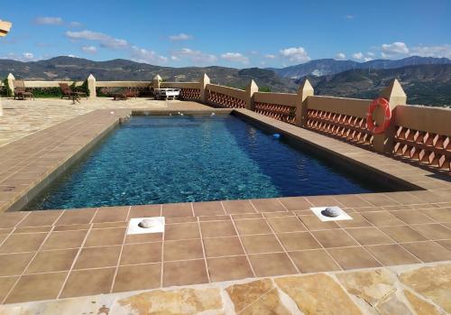 RestábalCortijo Don Enrique的一座位于庭院内的游泳池,庭院内以群山为背景