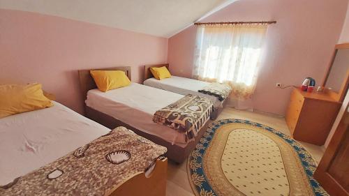 波格拉德茨Guest House Pogradeci的一间卧室设有两张床、一个窗口和椅子