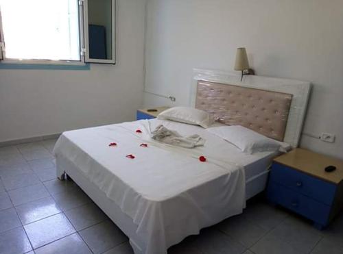 马赫迪耶Houria House Sable D'or的一间卧室配有一张白色的床铺,上面有红玫瑰