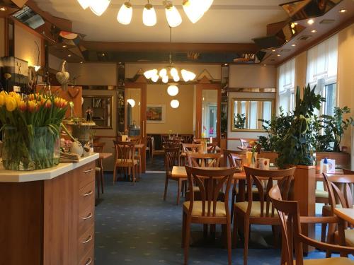 巴特索登-阿伦多夫Café Feldmann & Pension的一间带木椅和桌子的餐厅以及鲜花