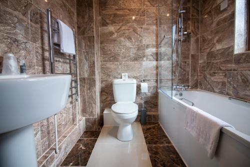 北安普敦聚焦威斯顿庄园酒店的浴室配有卫生间、浴缸和水槽。