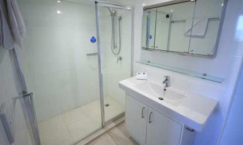黄金海岸图岗圣西蒙海滨公寓的白色的浴室设有水槽和淋浴。