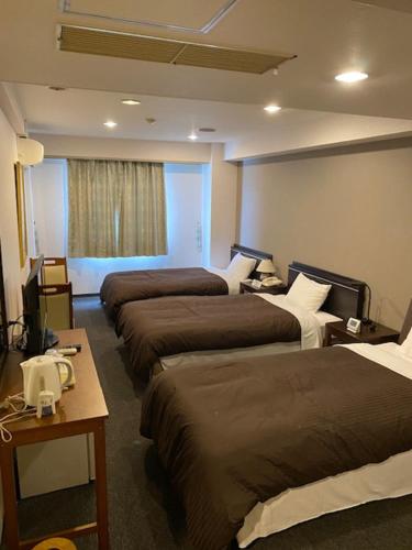 泉佐野丰荣酒店的酒店客房设有三张床和窗户。