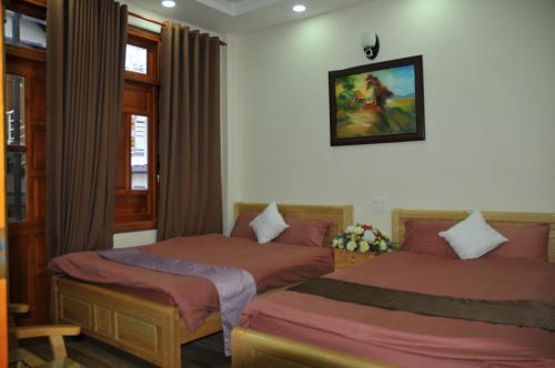 大叻Anh Trang Homestay的卧室配有两张床,墙上挂着一幅画