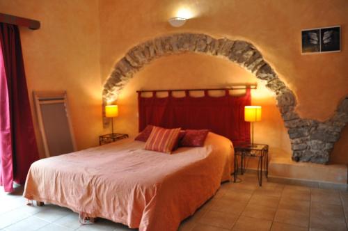 Moulès-et-Baucels布兰卡蒂庄园酒店的一间卧室设有一张带石墙的大床