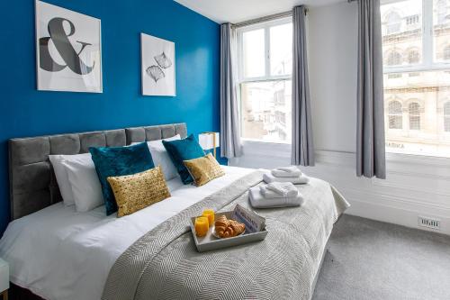 泰恩河畔纽卡斯尔Stylish Apartment in the heart of Newcastle centre的蓝色的卧室,配有一张床和食物托盘
