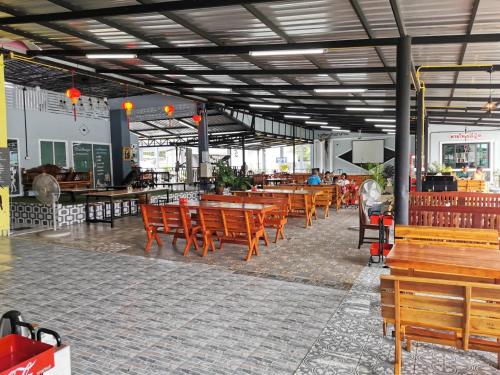 锡春Chaiyai River Front Hotel的一间空餐厅,配有木椅和桌子