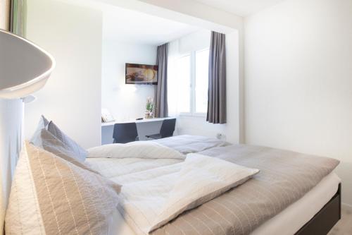 艾因西德伦Hotel Allegro Einsiedeln的白色卧室设有一张大床和窗户