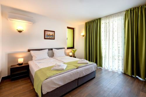 内塞伯尔Panorama Blue Family Hotel的一间卧室配有一张带绿色窗帘的大床