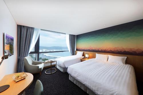 蔚山Mercure Ambassador Ulsan的酒店客房设有两张床和大窗户。