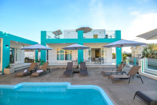 阿尔比恩Abiki Mauritius的一座带游泳池、椅子和遮阳伞的房子