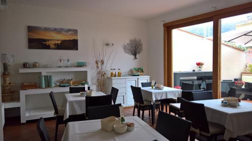 马达莱纳加里波第酒店的餐厅设有白色的桌椅和窗户。