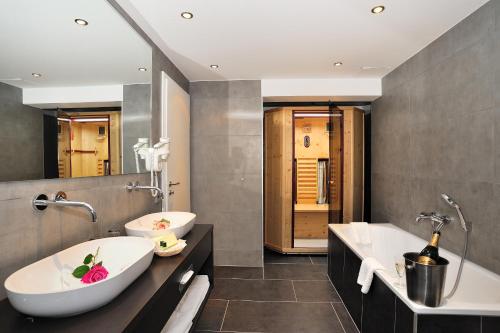 奥巴拉马高Landhotel Böld Oberammergau的一间带两个水槽和两个浴缸的浴室