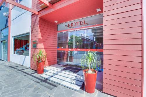 SapirangaHotel Comoditá Ltda的一座红色的建筑,在旅馆前有两株盆栽植物