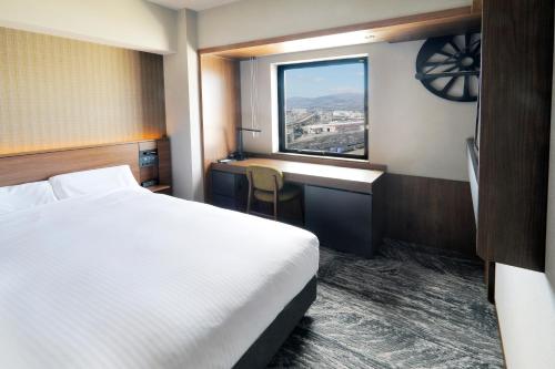 函馆JR Inn Hakodate的配有一张床、一张书桌和一扇窗户的酒店客房
