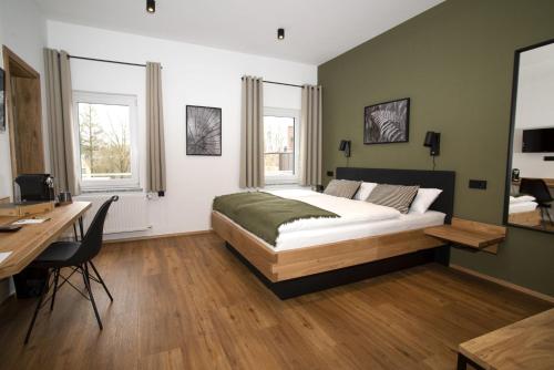 WiesauHolzfellas Home的一间卧室配有一张床、一张书桌和两个窗户。