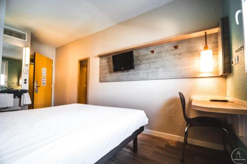 Yffiniac伊菲尼阿克圣布里厄宜必思快捷酒店的一间卧室配有一张床和一张书桌,墙上配有电视。