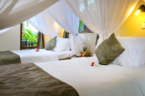 艾湄湾珊瑚景别墅酒店的一间卧室配有两张带白色床单和窗帘的床