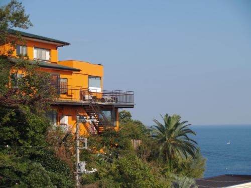 伊东休闲海滩公社（仅限成人）的一座黄色的房子,在山边,与大海