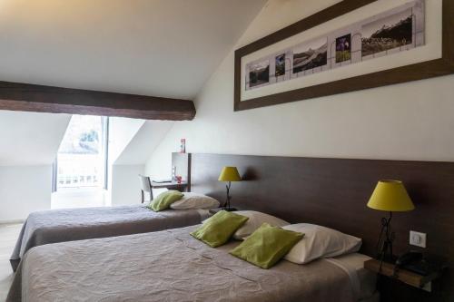 拉兰Hôtel d'Ossau的一间卧室配有两张带绿色枕头的床