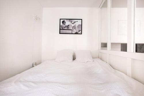 里尔LA CABANE Lille Centre的白色的房间里一张白色的床,墙上挂着一张照片