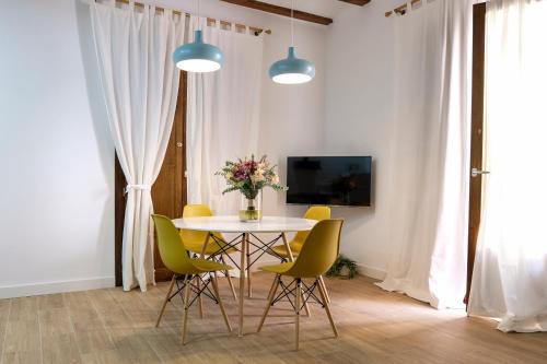 卡迪瓦LA MOMA Apartments & Room的一间带桌子和黄色椅子的用餐室