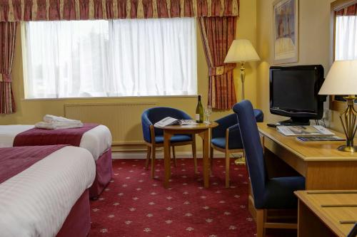 蒂弗顿Tiverton Hotel Lounge & Venue formally Best Western的酒店客房配有书桌、床和电视。