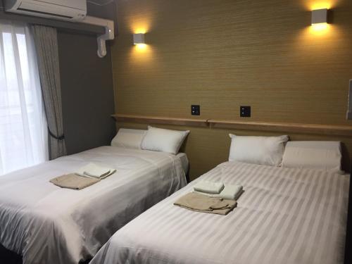 大村市Omura Station Hotel Nagasaki Airport的两张睡床彼此相邻,位于一个房间里