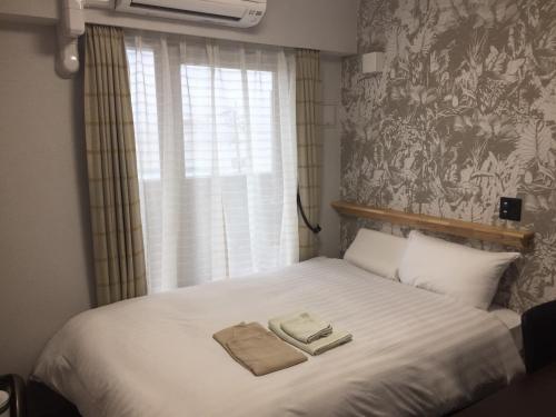 大村市Omura Station Hotel Nagasaki Airport的一间卧室配有一张床,上面有两条毛巾