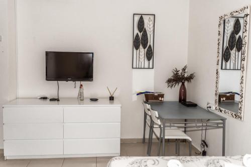 埃拉特סטודיו ליה - studio lia eilat的客厅配有书桌和白色墙壁上的电视