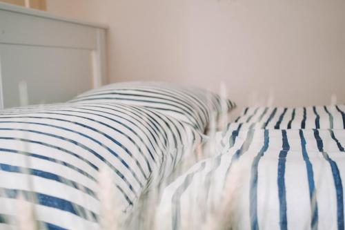 图恩NEB-THUN LODGE`s Appartement 1 Hilterfingen Ringstrasse 6的一张带蓝色和白色条纹床单的床和一个枕头