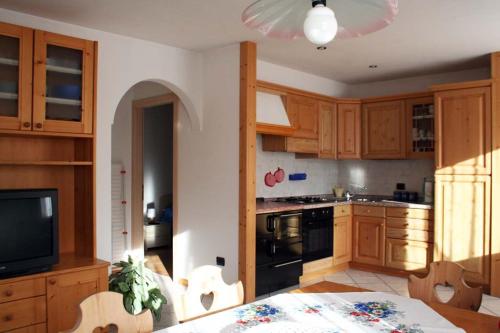 泰塞罗Appartamenti Piazzi的厨房配有木制橱柜、桌子和电视。