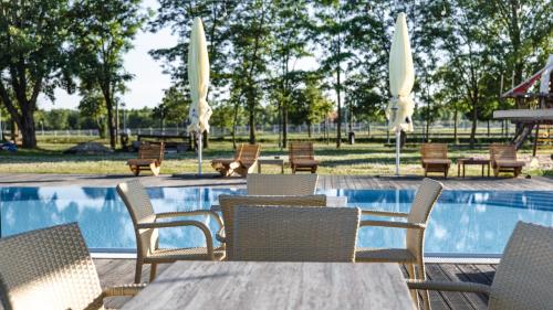 布拉迪斯拉发迪沃卡沃达酒店及公园的一组椅子和桌子,位于游泳池旁