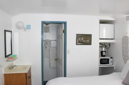 阿瓦隆荷摩沙酒店的一间卧室配有一张床,浴室设有水槽